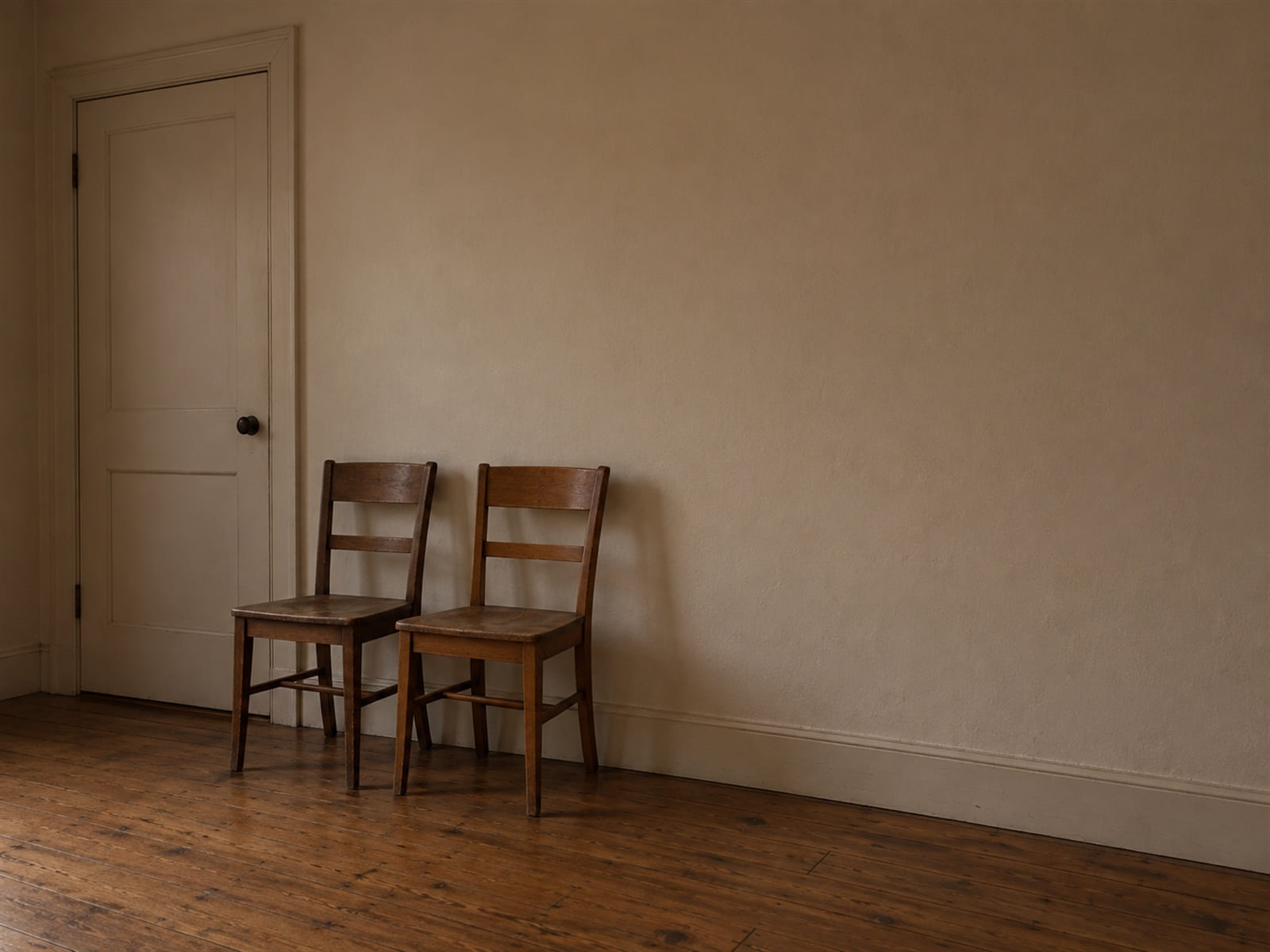 An empty corridor outside an interview room with two chairs against the wall