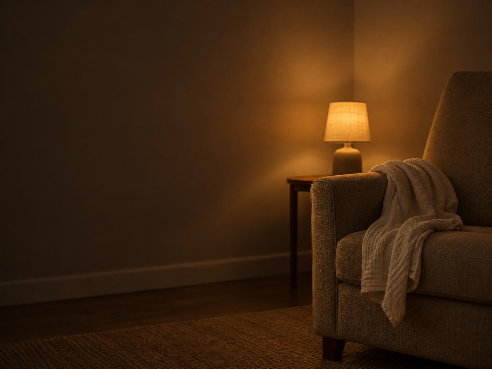 A folded muslin cloth over the arm of a nursing chair beside a small lamp turned low