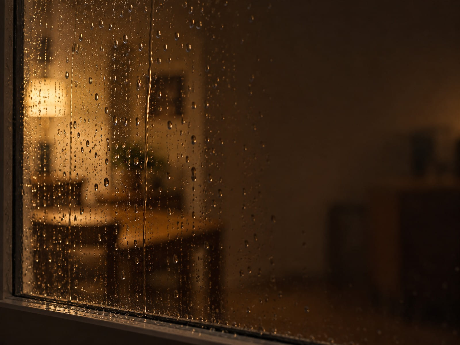 A window with rain on it, the room behind out of focus