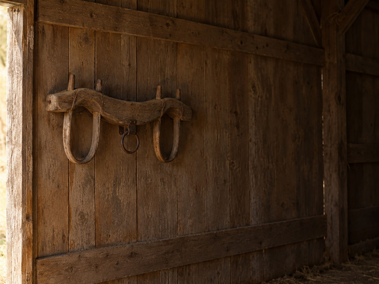 A wooden yoke hanging on the wall of an old barn in daylight