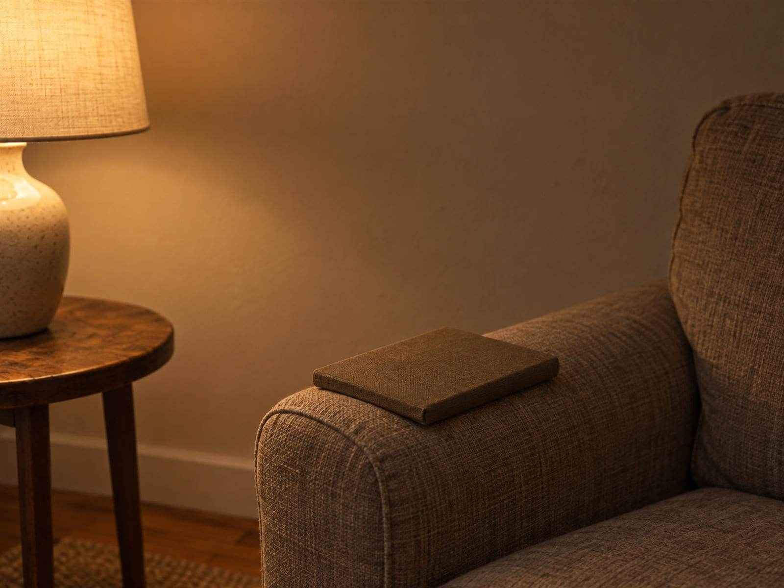 A stack of read paperbacks beside a lamp, one left open face down